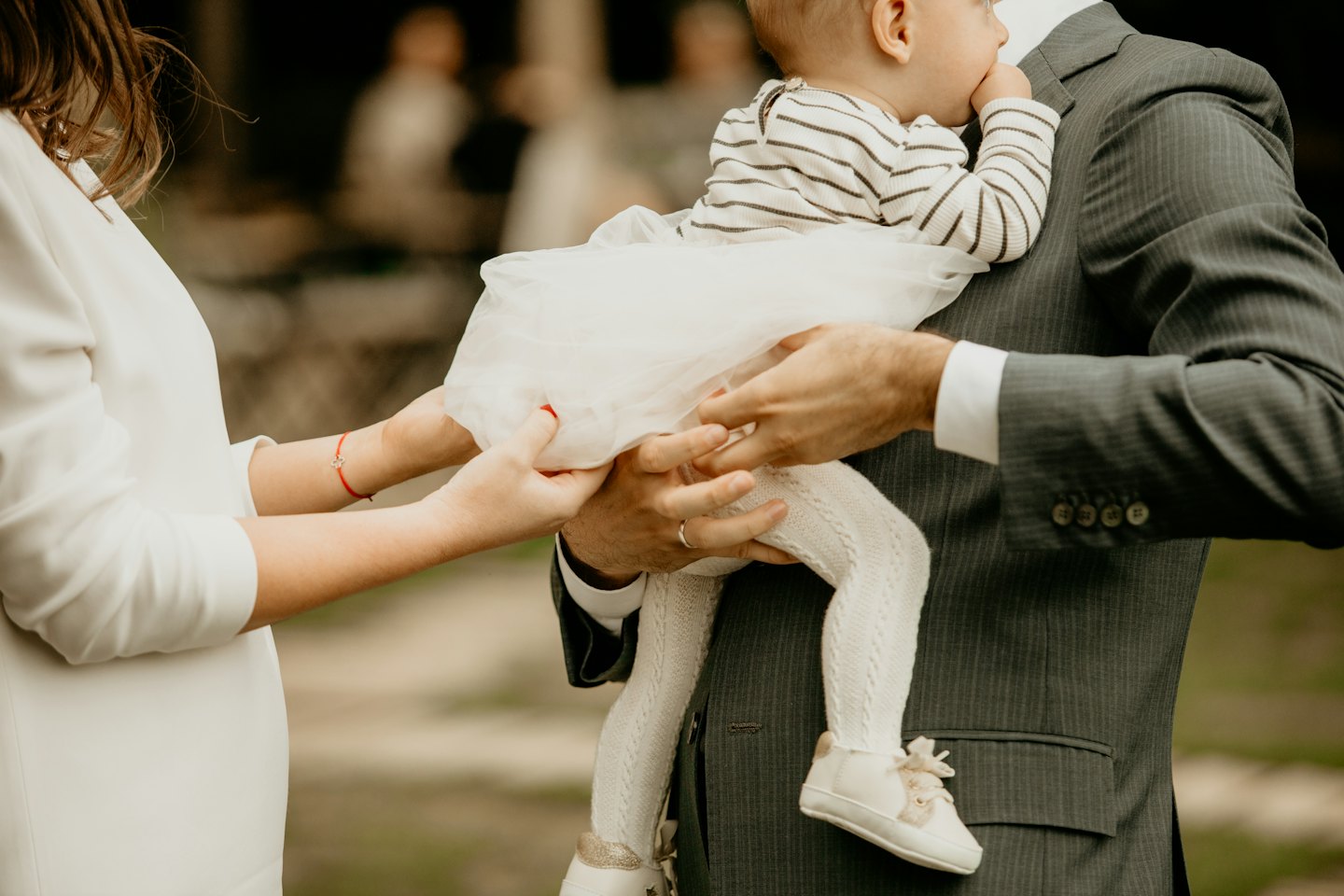 Parents holding their baby in a white tulle skirt.