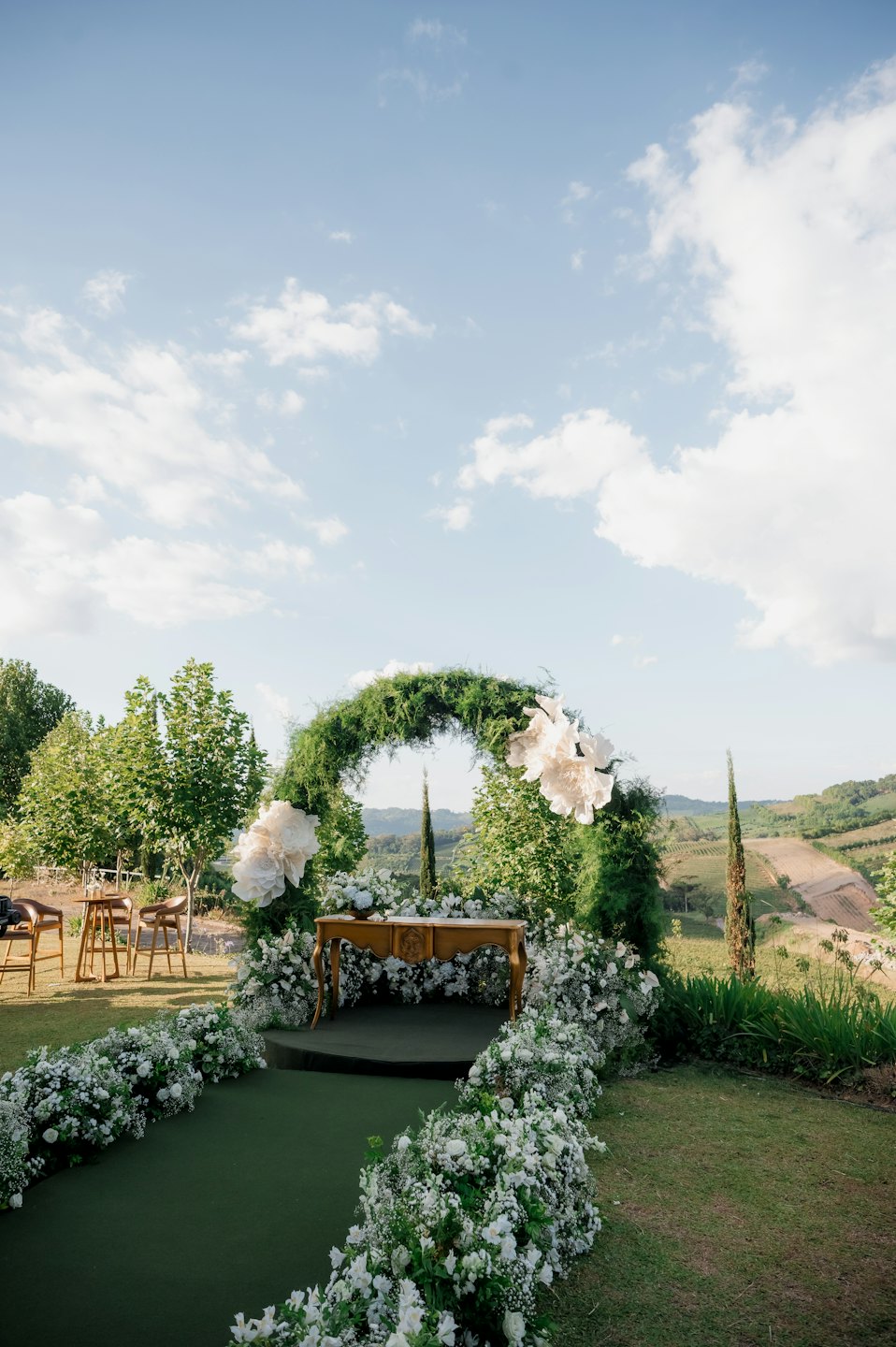 Outdoor wedding ceremony arch with flowers and wooden altar.