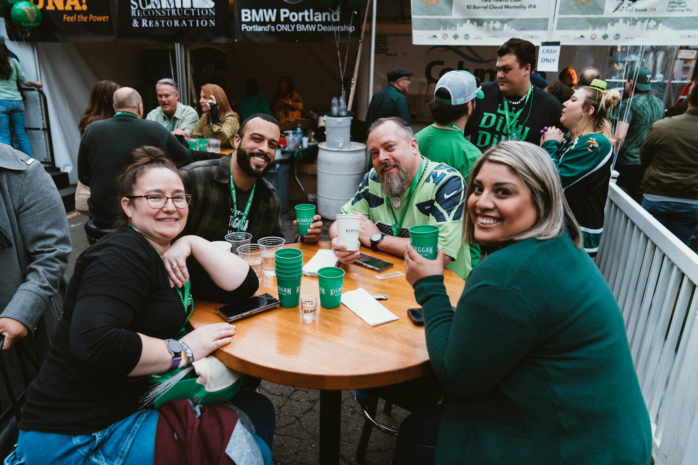 Friends wearing green gather around a wooden table at an event.