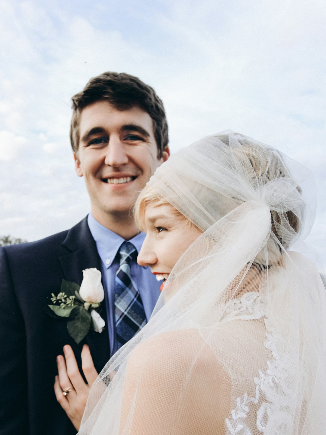 A wedding couple smiling together in their bridal attire.
