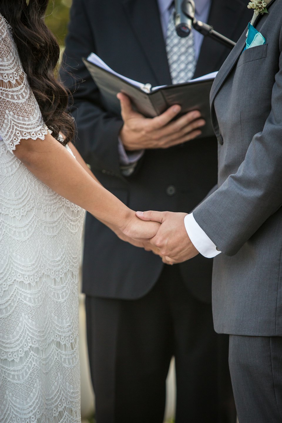 A couple holds hands during their outdoor wedding ceremony.